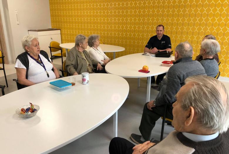 Grupa seniorów na spotkaniu z policjantem w Dziennym Domu Senior +