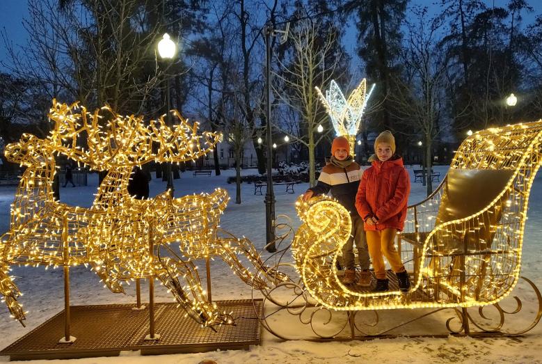 iluminowana ozdoba świąteczna w parku miejskim, dwoje dzieci