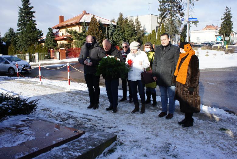 Siedem osób składających kwiaty i znicze