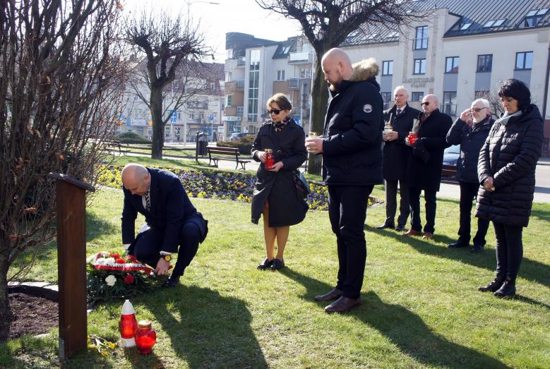 Kwiaty i znicze składają Burmistrz Miasta Mława Sławomir Kowalewski, Naczelnik Wydziału Komunikacji Społecznej i Medialnej Urzędu Miasta Mława Magdalena Grzywacz, Zastępca Burmistrza Miasta Mława Szymon Zejer i Dyrektor Miejskiego Domu Kultury w Mławie Edyta Suszek