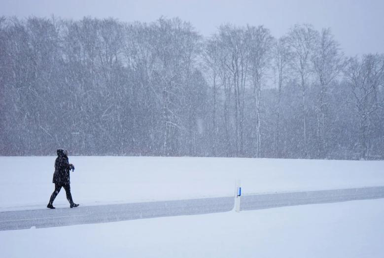 Człowiek idący drogą podczas opadów śniegu