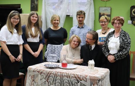 Uczestnicy Narodowego Czytania w Miejskiej Bibliotece Publicznej w Mławie: z przodu dwie osoby siedzą przy stole, z tyłu sześć osób stoi.