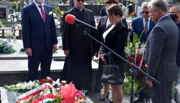Uczestnicy uroczystości składają kwiaty i zapalone znicze