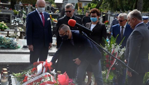 Uczestnicy uroczystości składają kwiaty i zapalone znicze