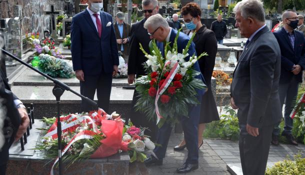 Uczestnicy uroczystości składają kwiaty i zapalone znicze