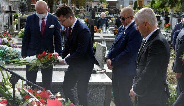 Uczestnicy uroczystości składają kwiaty i zapalone znicze