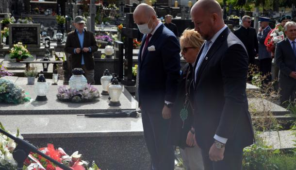 Uczestnicy uroczystości składają kwiaty i zapalone znicze