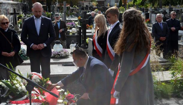 Uczestnicy uroczystości składają kwiaty i zapalone znicze