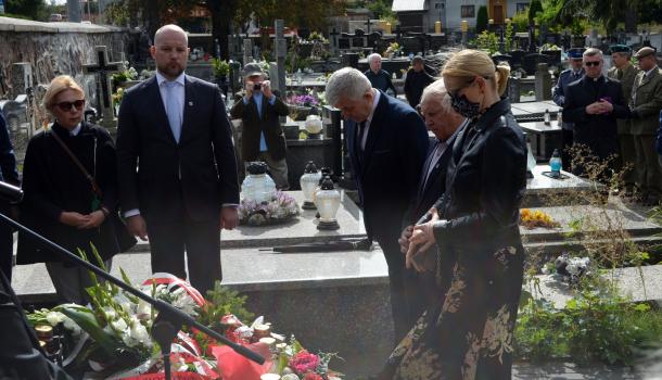 Uczestnicy uroczystości składają kwiaty i zapalone znicze
