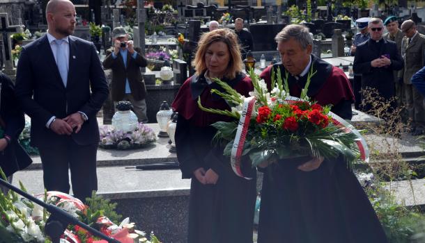 Uczestnicy uroczystości składają kwiaty i zapalone znicze