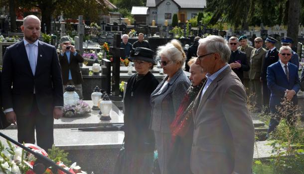 Uczestnicy uroczystości składają kwiaty i zapalone znicze