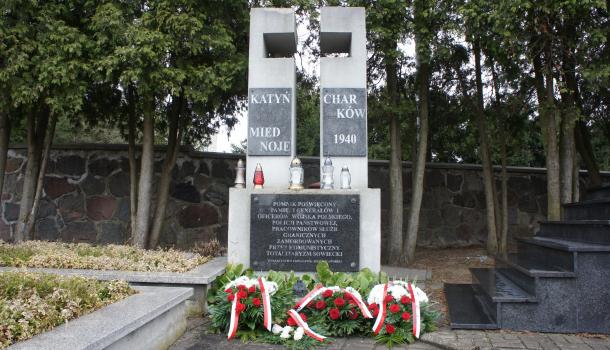 Kwiaty i znicze złożone pod pomnikiem na cmentarzu parafialnym