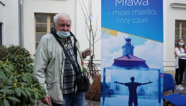 Mieszkaniec Mławy z sadzonką drzewa przy rollupie promocyjnym