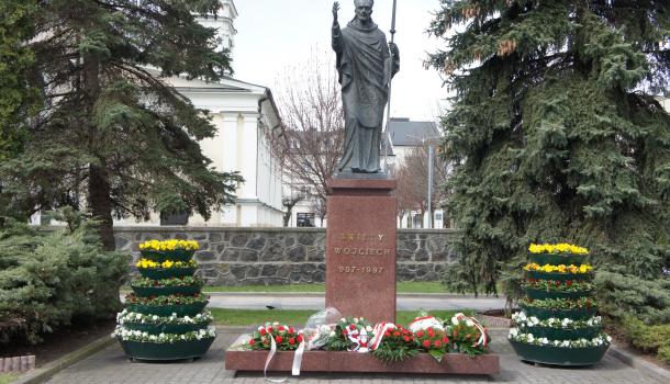 Pomnik św. Wojciecha ze złożonymi kwiatami