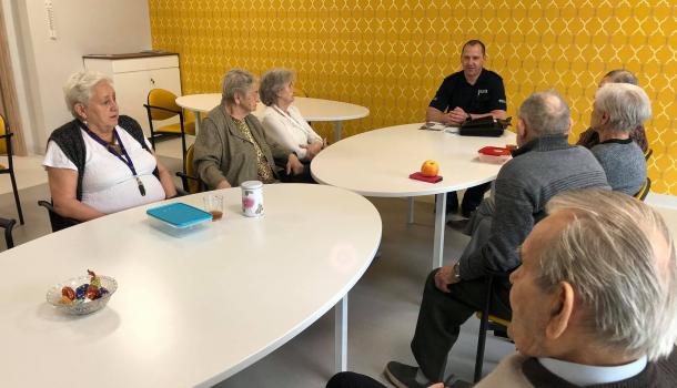 Grupa seniorów na spotkaniu z policjantem w Dziennym Domu Senior +