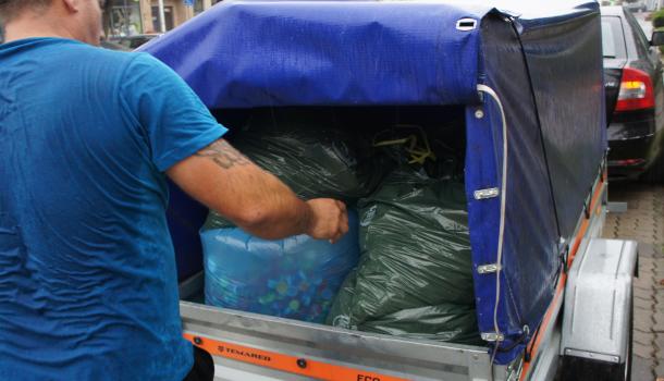 Mężczyzna ładujący worki z nakrętkami na przyczepkę samochodową