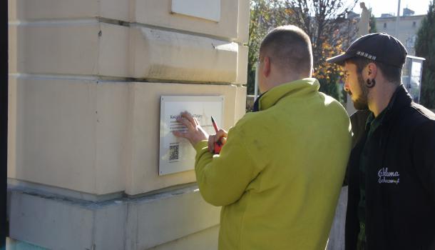montaż tabliczki na ogrodzeniu kościoła pw. Świętej Trójcy